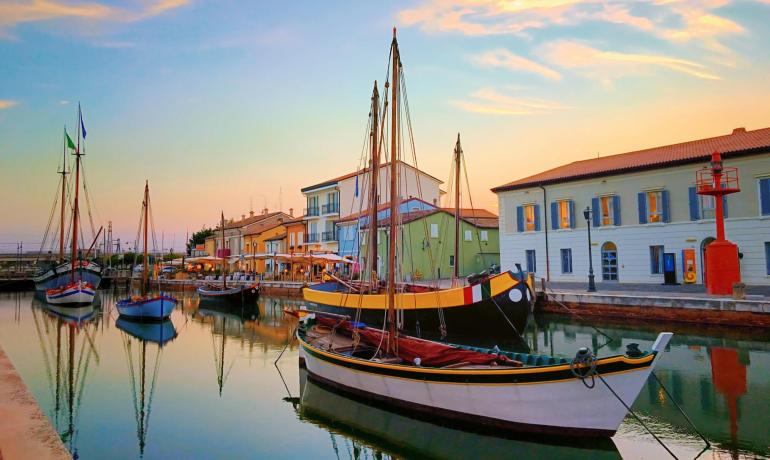 Barche colorate ormeggiate lungo un pittoresco canale al tramonto.
